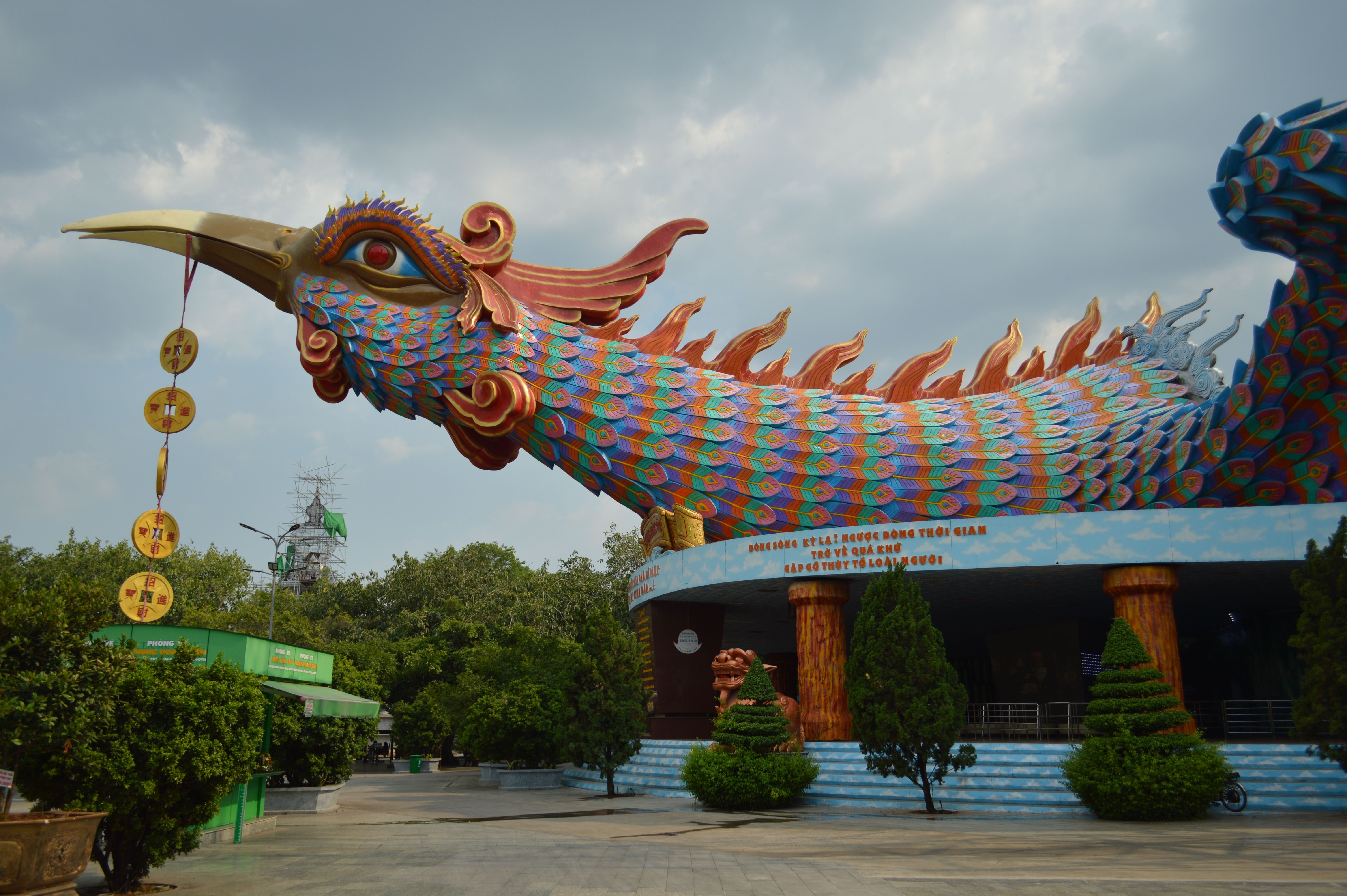 Escultura monumental de Fenghuang com penas coloridas em templo asiático